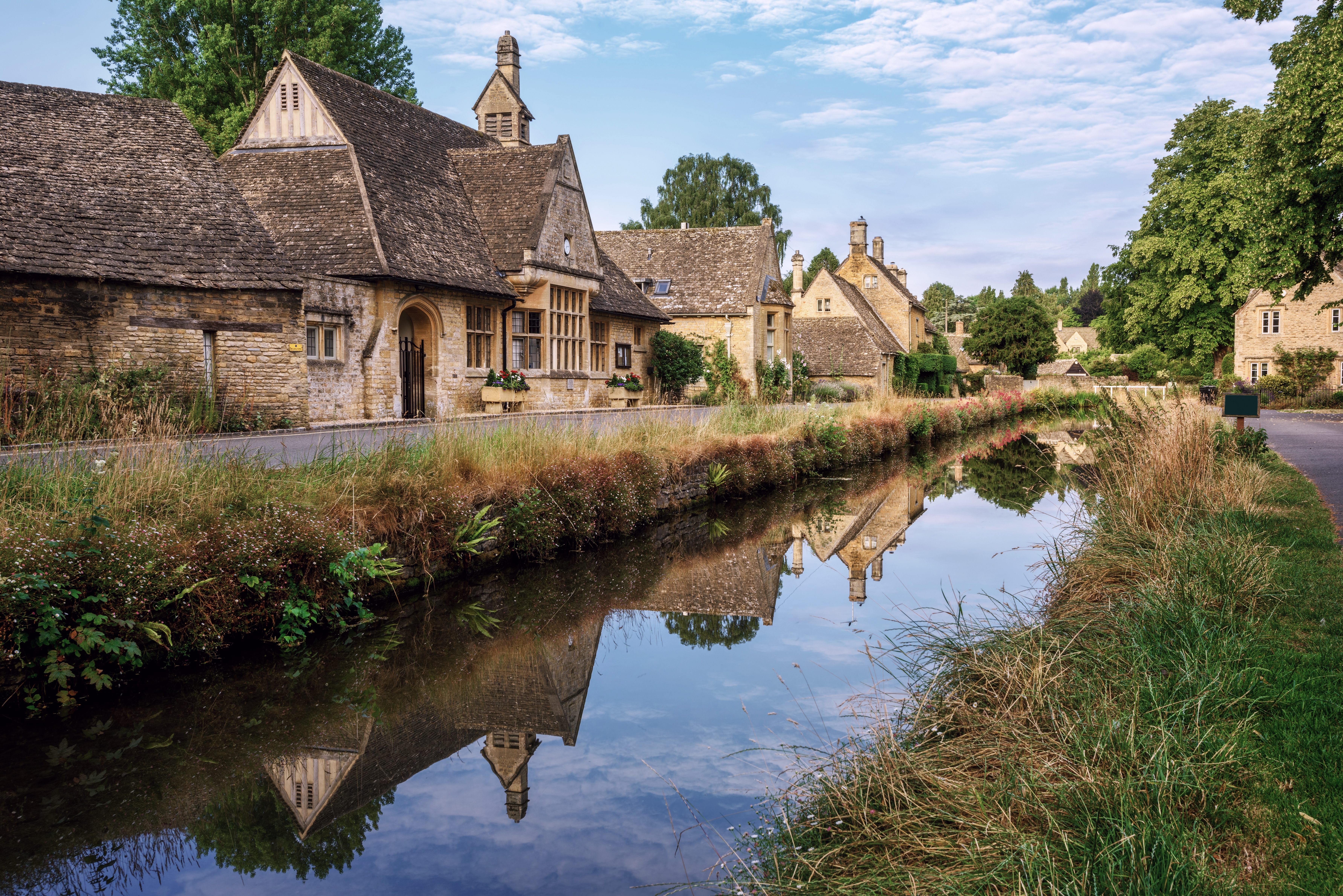traditional stone houses reflecting in a river on a summer day in lower slaughter village in cotswolds england united kingdom lower slaughter village is one of the most visited sites in cotswolds