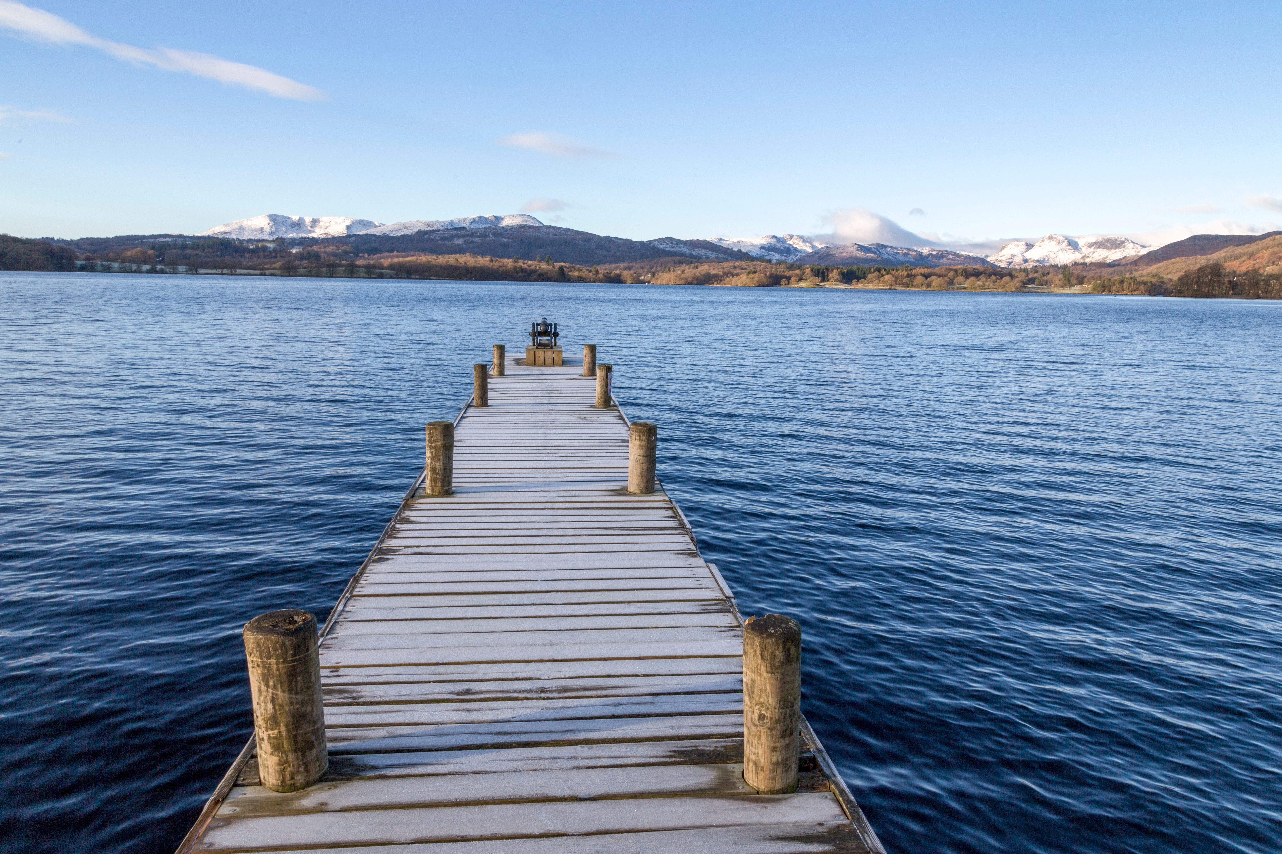 frost covered jetty at the north end of windermere near ambleside with rugged snow covered mountains including helvellyn lake district national park